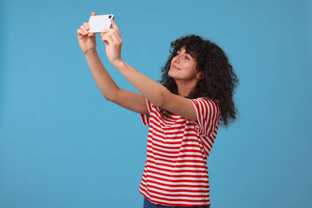 istock Beautiful young woman taking selfie on light blue background 1683220312