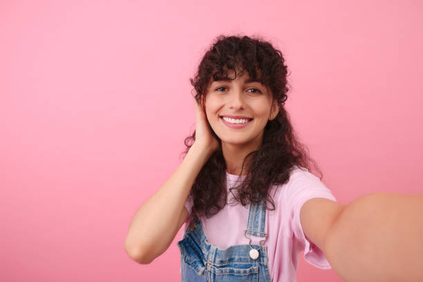 istock Beautiful woman taking selfie on pink background 1683220328