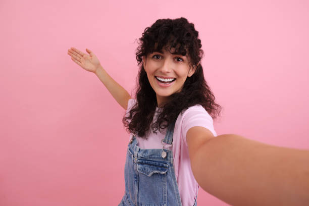 istock Beautiful woman taking selfie on pink background 1683220844