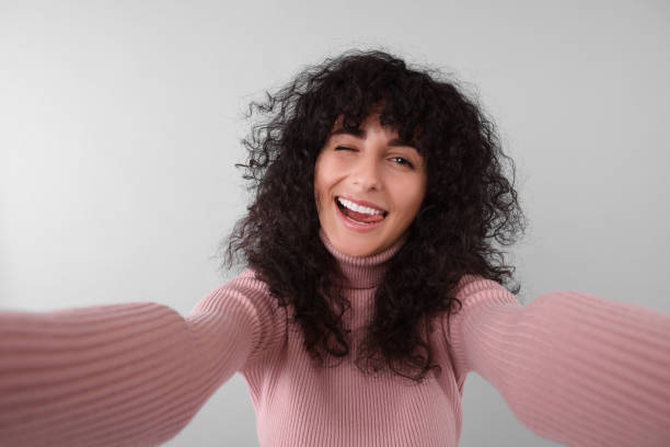 istock Beautiful young woman taking selfie on light grey background 1683221380