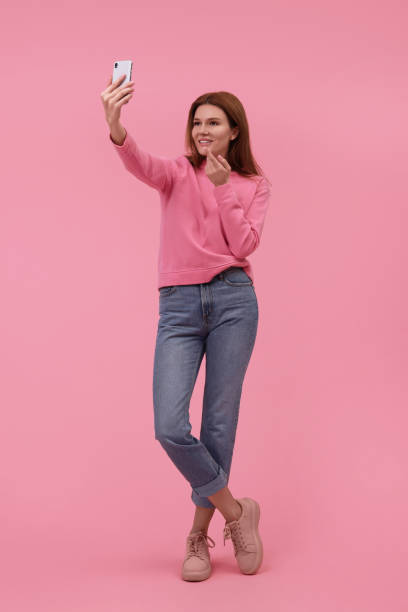 istock Beautiful woman taking selfie on pink background 1683225550