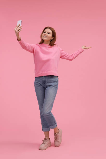 istock Beautiful woman taking selfie on pink background 1683226055