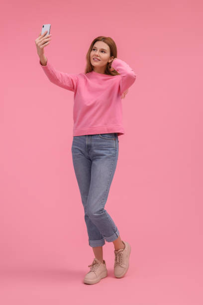 istock Beautiful woman taking selfie on pink background 1683226058