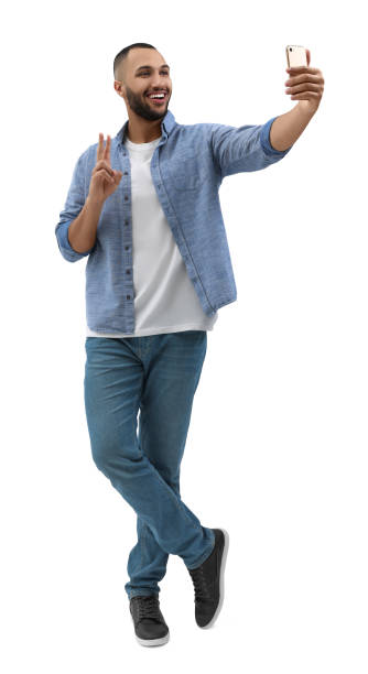 istock Smiling young man taking selfie with smartphone and showing peace sign on white background 1683237265