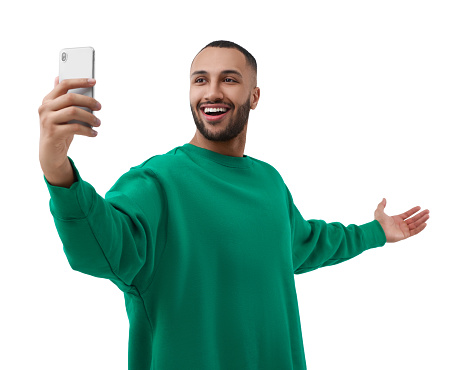 Smiling young man taking selfie with smartphone on white background