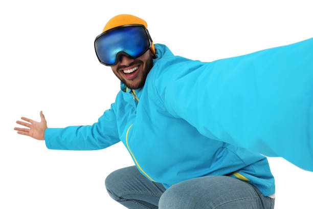 Smiling young man in ski goggles taking selfie on white background