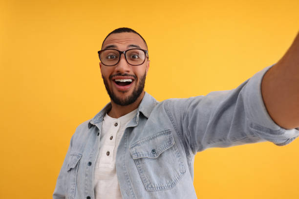 istock Smiling young man taking selfie on yellow background 1683239982
