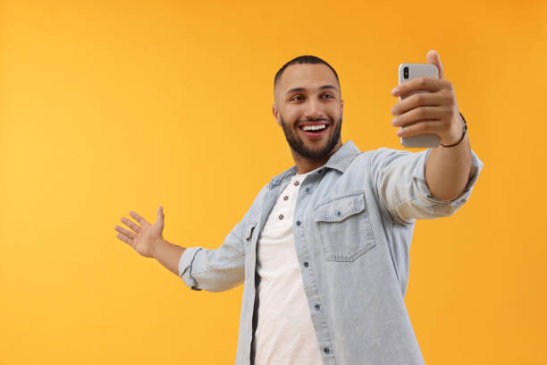 istock Smiling young man taking selfie with smartphone on yellow background 1683240013
