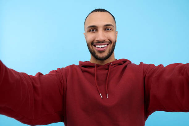 istock Smiling young man taking selfie on light blue background 1683240554