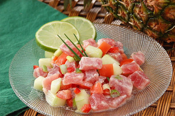 Poussin cru or raw fish with pineapple Poisson Cru à la Tahitienne (or E'ia Ota) – the unofficial national dish of French Polynesia – consists of raw ahi tuna tossed with coconut milk, lime, cucumbers, tomatoes, and scallions. seviche photos stock pictures, royalty-free photos & images