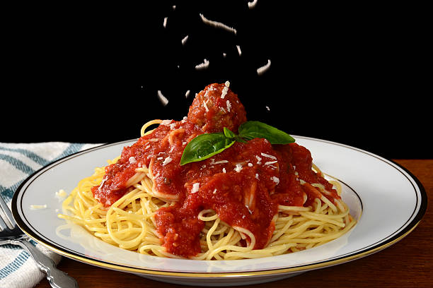 Spaghetti and Meatballs Freshly grated parmesan cheese falls on a plate of spaghetti and meatballs. Plate of Spaghetti stock pictures, royalty-free photos & images