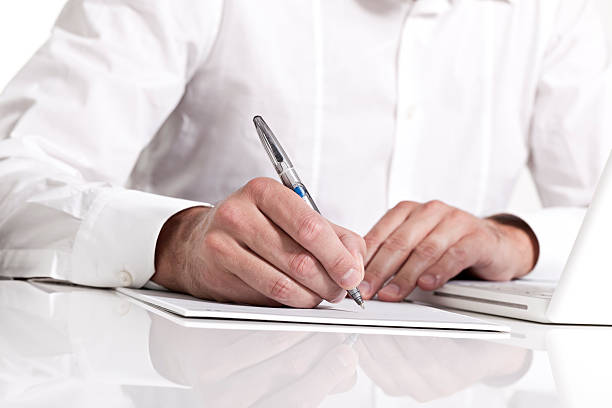 Businessman holding a pen & taking notes on paper