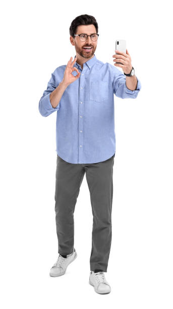 istock Smiling man taking selfie with smartphone and showing OK gesture on white background 1683245475
