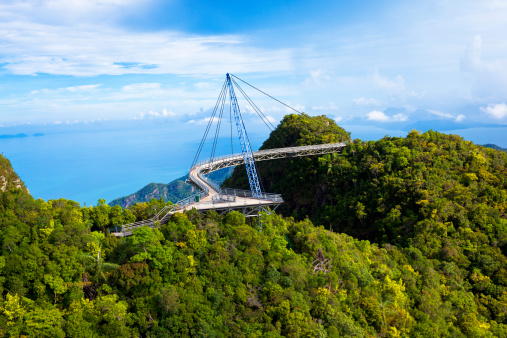 amazing cable bridge over the tropical rainforest island landscape in langkawi, malaysia.