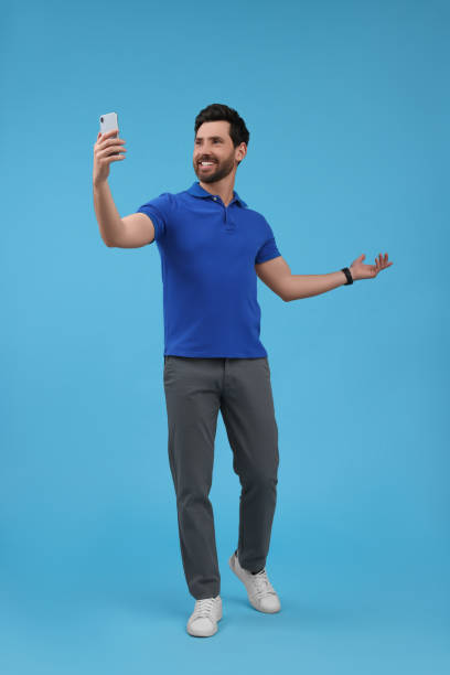 istock Smiling man taking selfie with smartphone on light blue background 1683246000