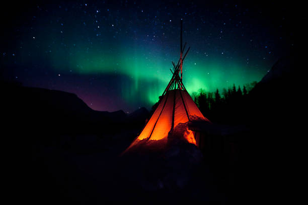 The Northern Lights Aurora Aurora with Laavo teepee silhouetted in foreground. Near Tromso, Norway. Some noise due to long exposure. tromso stock pictures, royalty-free photos & images