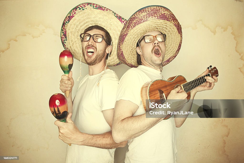Funny Mariachi Band with Sombreros Two men sing happily and enthusiastically with goofy expressions on their face, glasses, and big sombreros, both playing instruments (maracas and ukelele).  Aged yellow paper background to give a rustic feel.  Horizontal. Humor Stock Photo