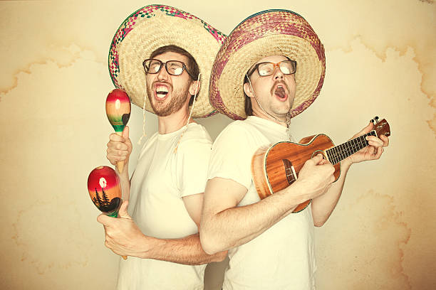 Funny Mariachi Band with Sombreros Two men sing happily and enthusiastically with goofy expressions on their face, glasses, and big sombreros, both playing instruments (maracas and ukelele).  Aged yellow paper background to give a rustic feel.  Horizontal. maraca stock pictures, royalty-free photos & images