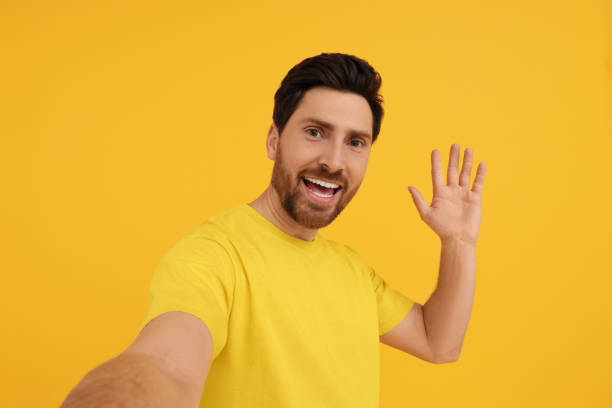 istock Smiling man taking selfie on yellow background 1683249157