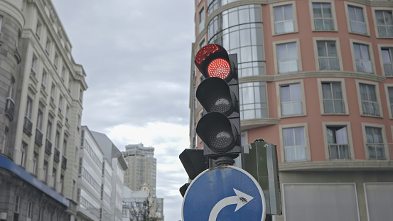 In the heart of the city, the urban traffic unfolds with the iconic red signal on a traffic light, signaling a momentary pause in the bustling flow of vehicles. Simultaneously, the adjacent road sign gives a green light for a right turn, allowing drivers to navigate the intersection safely. It's a snapshot of traffic control and safety measures, where the harmony of road signs and signals guides the course of vehicles, ensuring a smooth and regulated movement through the urban landscape.