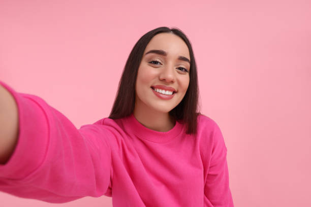 istock Smiling young woman taking selfie on pink background 1683266627