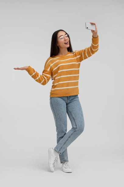 istock Smiling young woman taking selfie with smartphone on white background 1683268716