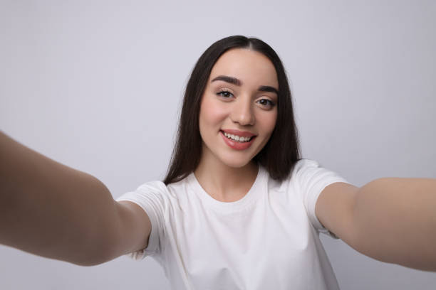 istock Smiling young woman taking selfie on white background 1683271961