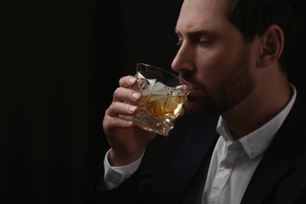 istock Man in suit drinking whiskey on black background. Space for text 1683286893