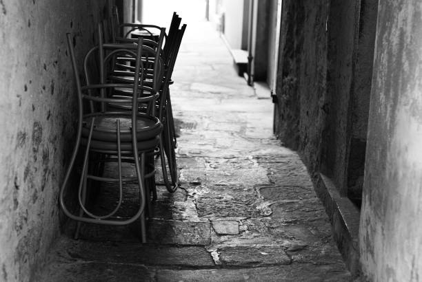 istock Chairs back lit in narrow italian alley 168329046