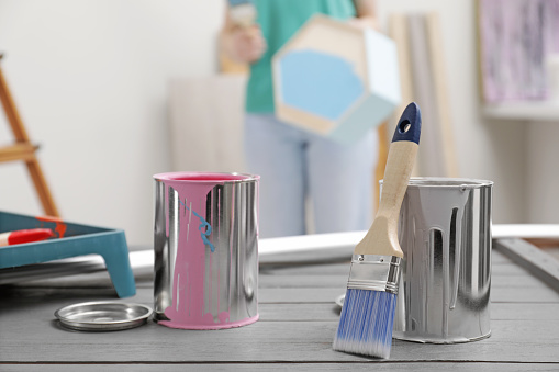 Cans of paint and brush on grey wooden table indoors