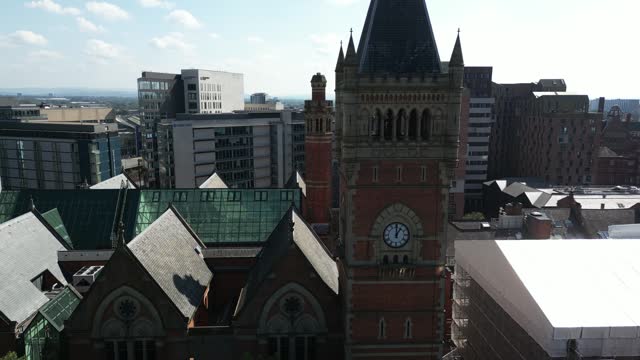 Aerial drone flight around Manchester Crown Court rooftop showcasing a skyline of skyscrapers in the background