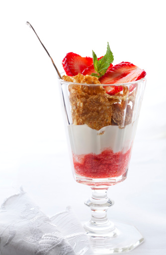 Closeup of a glass  creamy yogurt with fresh strawberries and wheat flakes