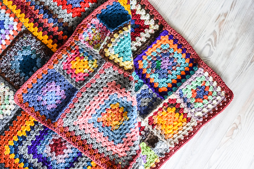 Closeup of senior woman hands knitting colorful blanket by hand