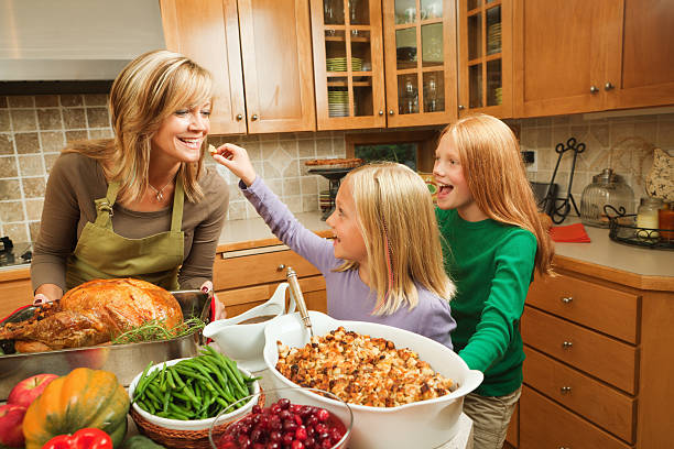 familia thanksgiving con madre, hijas vacaciones de una cena en la cocina a la vista en la cocina - stereotypical housewife little girls family domestic kitchen fotografías e imágenes de stock