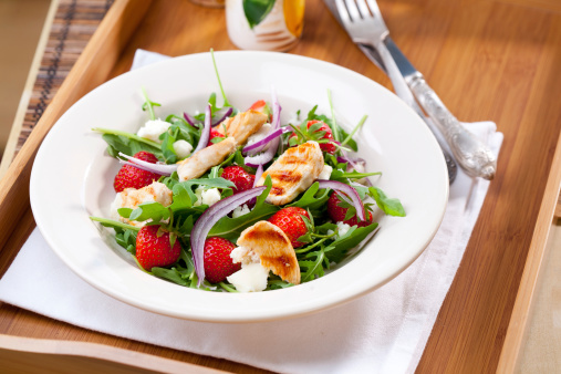 Grilled chicken on arugula salad with strawberries and red onion