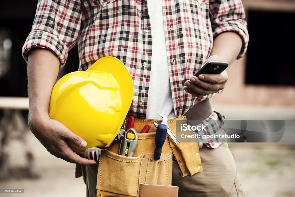 Trabajador de la construcción'escribiendo en un teléfono inteligente - Foto de stock de Sector de la construcción libre de derechos