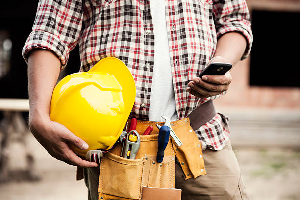 trabalhador de construção digitando em um smartphone - construction worker architect construction manual worker - fotografias e filmes do acervo