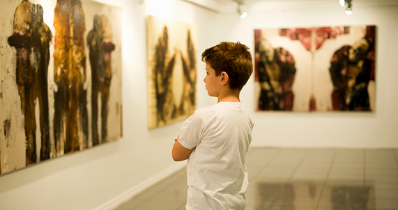 9 years old boy visiting an art gallery and looking to the paintings… 