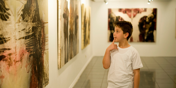 9 years old boy visiting an art gallery and looking to the paintings… 