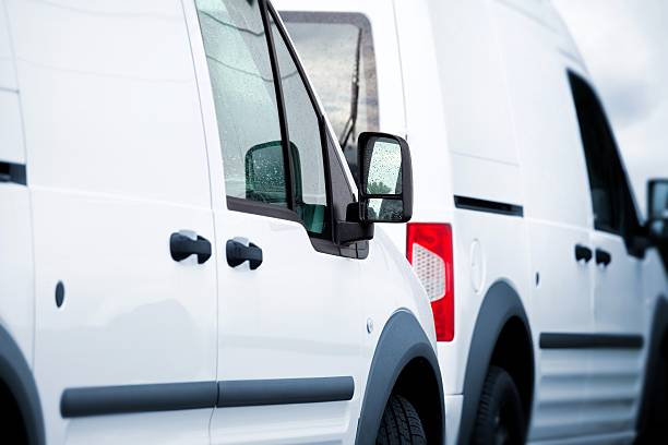 Two white vans in a parking lot A close up of two blanc white vans / transporters / service vehicles in a parking lot. The service vehicles are white. The vans are horizontally shot in an angled view. There are just white transporters no humans. More service vehicles and cars in my portfolio. convoy stock pictures, royalty-free photos & images