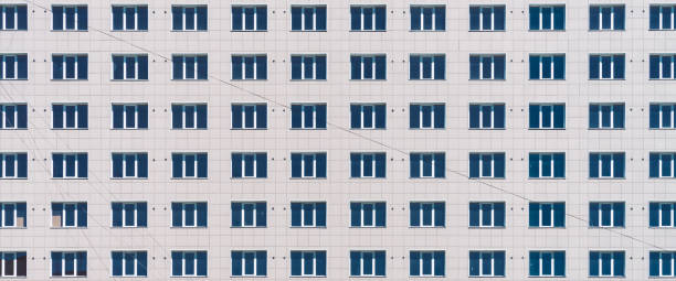 geometrischer hintergrund mit vielen fensterreihen. einfaches hochhaus in klassischem design. realistisches konzept des bürogebäudes. hintergrund, textur des mehrfamilienhauses. viele fenster an großen wänden in nahaufnahme. - architecture classic close up office building stock-fotos und bilder