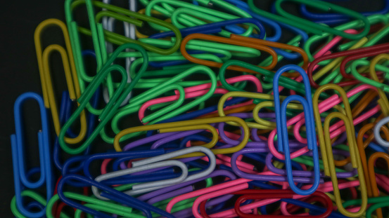 Colorful paper clips isolated on black background