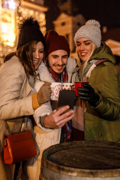 istock Friends taking selfies while enjoying mulled wine in Christmas themed mugs 1683595353
