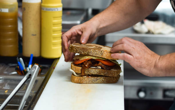 istock Restaurant employee preparing club sandwich for customer order 1683602346