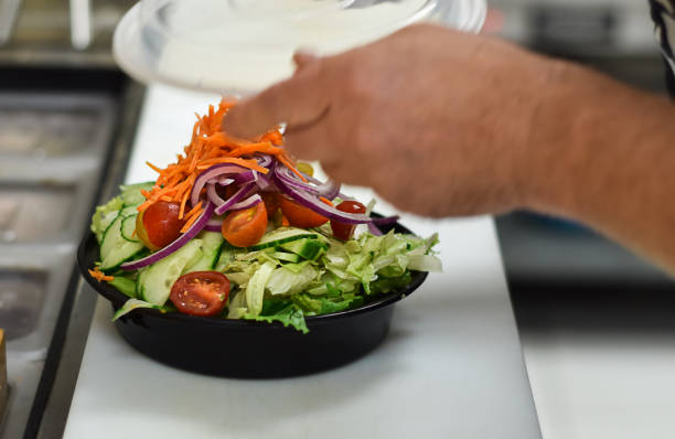 istock Restaurant employee packing salad in plastic container for take out order 1683602831