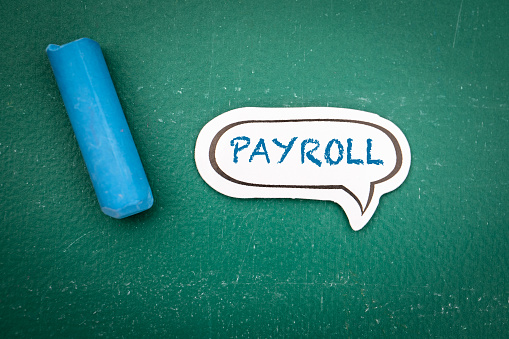 Payroll Concept. Speech bubble with text on a green chalkboard background.