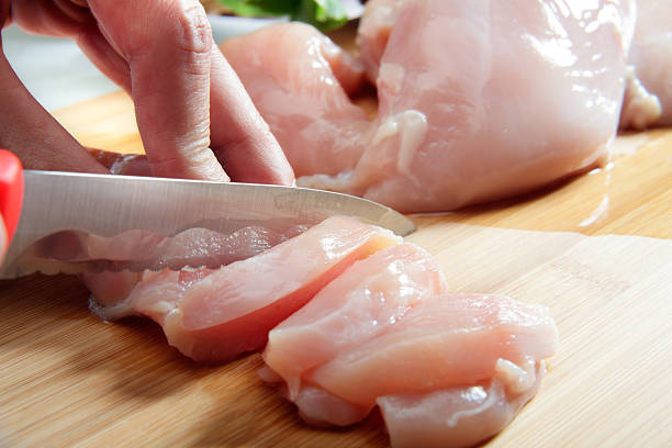 Man's hand cutting chicken breast Man's hand cutting raw chicken breast. Selective focus chicken breast photos stock pictures, royalty-free photos & images