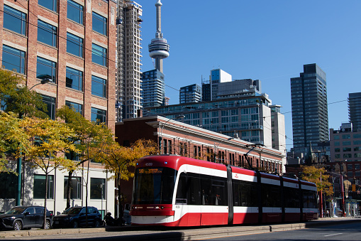 A TTC streetcar moves up Spadina Avenue in downtown Toronto, with the CN Tower seen in the background. Pictured in the fall, autumn and on a clear day.