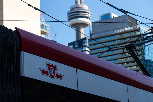 The TTC, Toronto Transit Commission logo is seen on the side of a TTC streetcar with the CN Tower seen in the background.