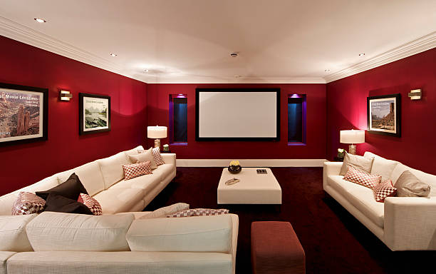 fabulous cinema room a cinema room in an expensive new home with large comfortable cream coloured settees, silk cushions and a foot stool. On either side of the screen are recessed windows with electronic blinds (lowered) and alcove lights. The pictures on the wall are the photographer's. alcove stock pictures, royalty-free photos & images